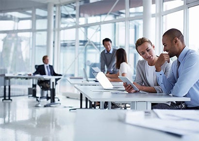 Business colleagues discussing over digital tablet at desk in office