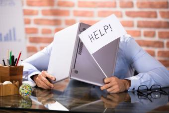 service desk man with head down and a help sign over laptop