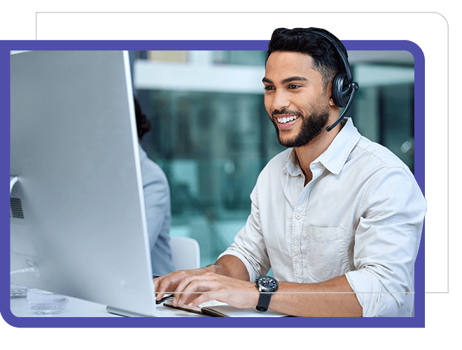 Young man, smiling at computer screen with headphones.