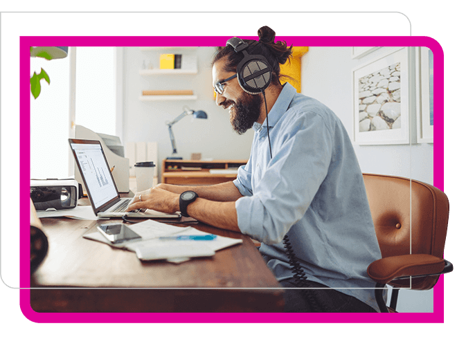 bearded man with headphone smiling at laptop