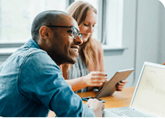 A man and a woman sitting at a desk in a brightly lit office setting